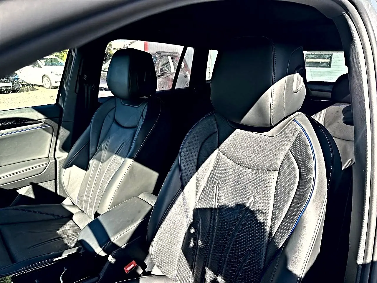 Vue intérieure des sièges avant en cuir noir Vienna avec surpiqûres bleues du Volkswagen Tiguan 2024 gris dauphin.