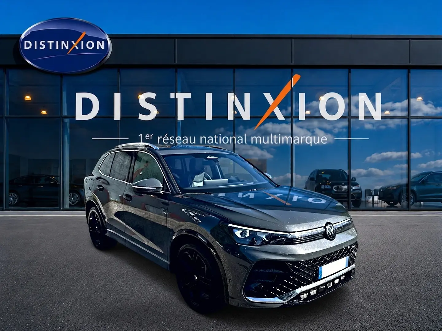 Volkswagen Tiguan gris dauphin en 3/4 avant droit, avec jantes noires et calandre R-Line distinctive.