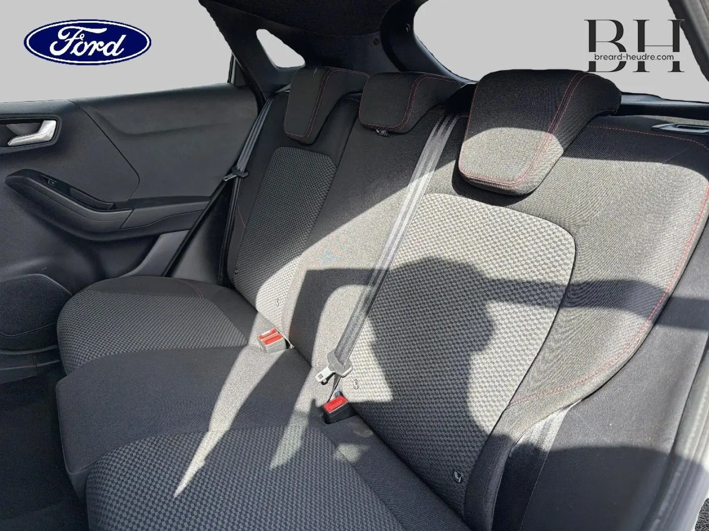 Vue intérieure de la banquette arrière côté gauche du Ford Puma 2024 avec tissu noir et surpiqûres rouges.