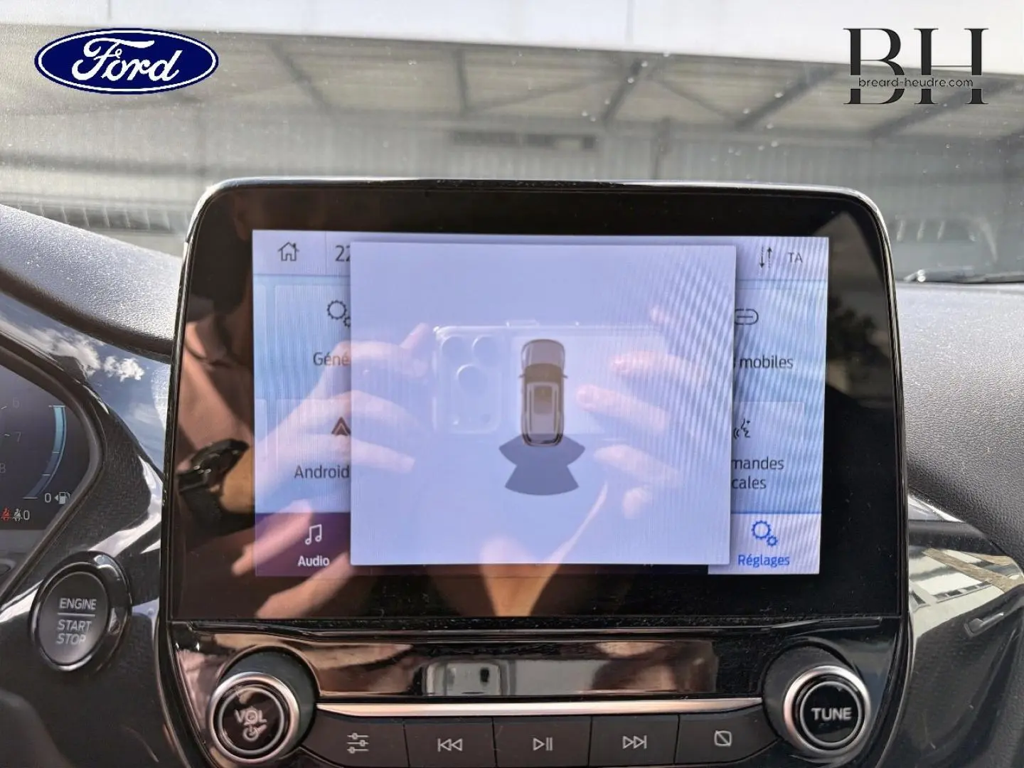 Écran tactile central du Ford Puma 2024 en gros plan, avec affichage du système d’aide au stationnement et bouton start/stop visible.