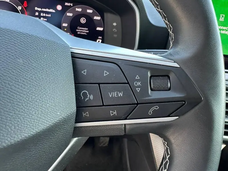 Gros plan sur les commandes au volant à droite du SEAT LEON ST 2025, avec boutons multifonctions et volant en cuir noir.