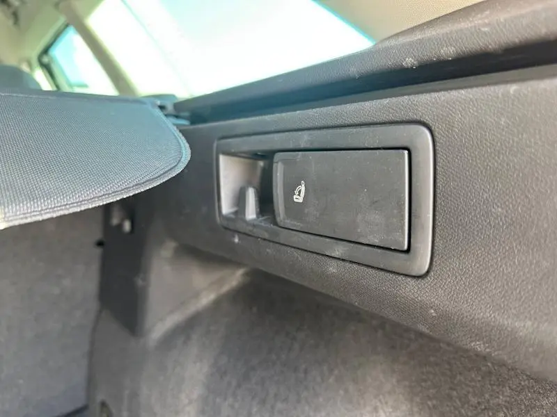 Détail du levier de rabattement des sièges arrière dans le coffre d’un SEAT LEON ST gris métallisé, vue rapprochée.