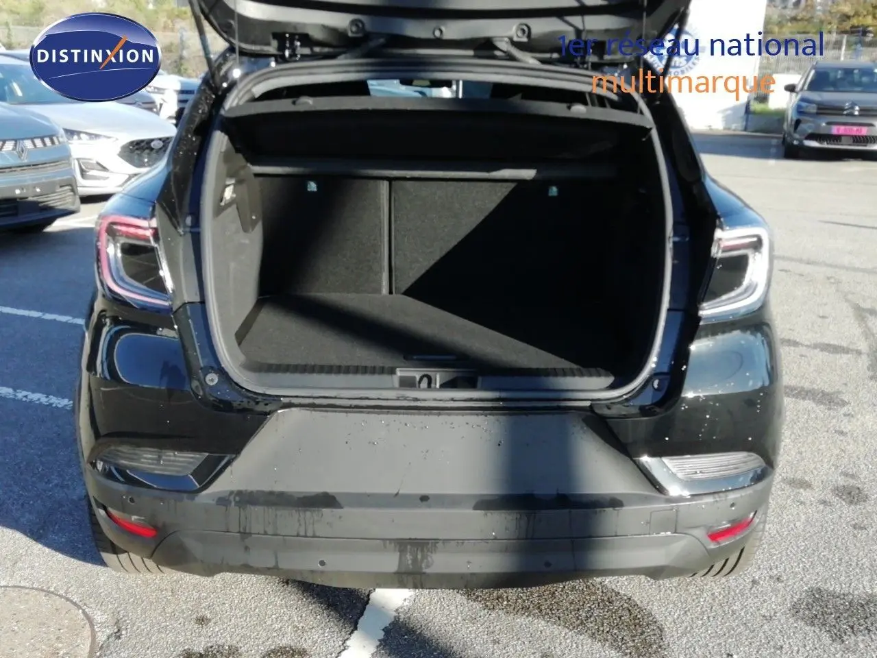 Vue arrière d'un Renault Captur noir étoile métal 2026 avec coffre ouvert sur un parking extérieur.