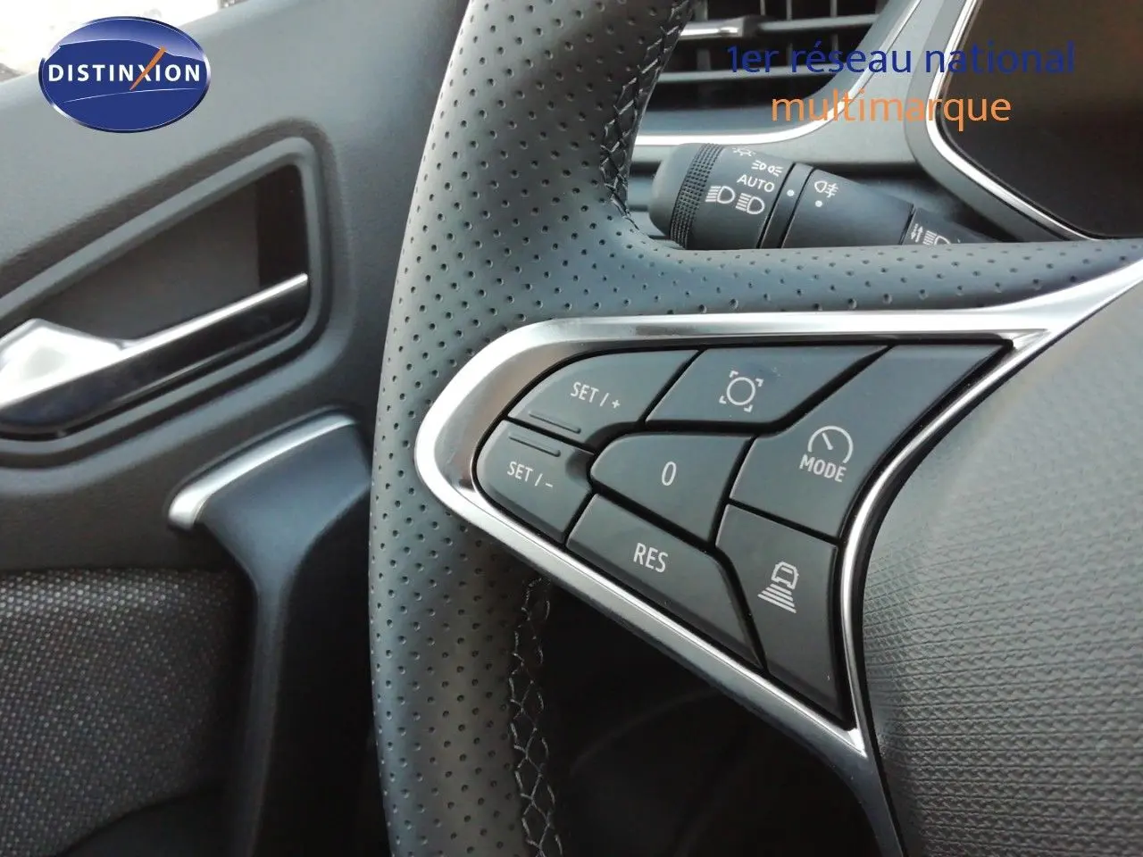 Gros plan sur les commandes au volant en cuir perforé noir du Renault Captur E-Tech 2026, avec détails chromés.