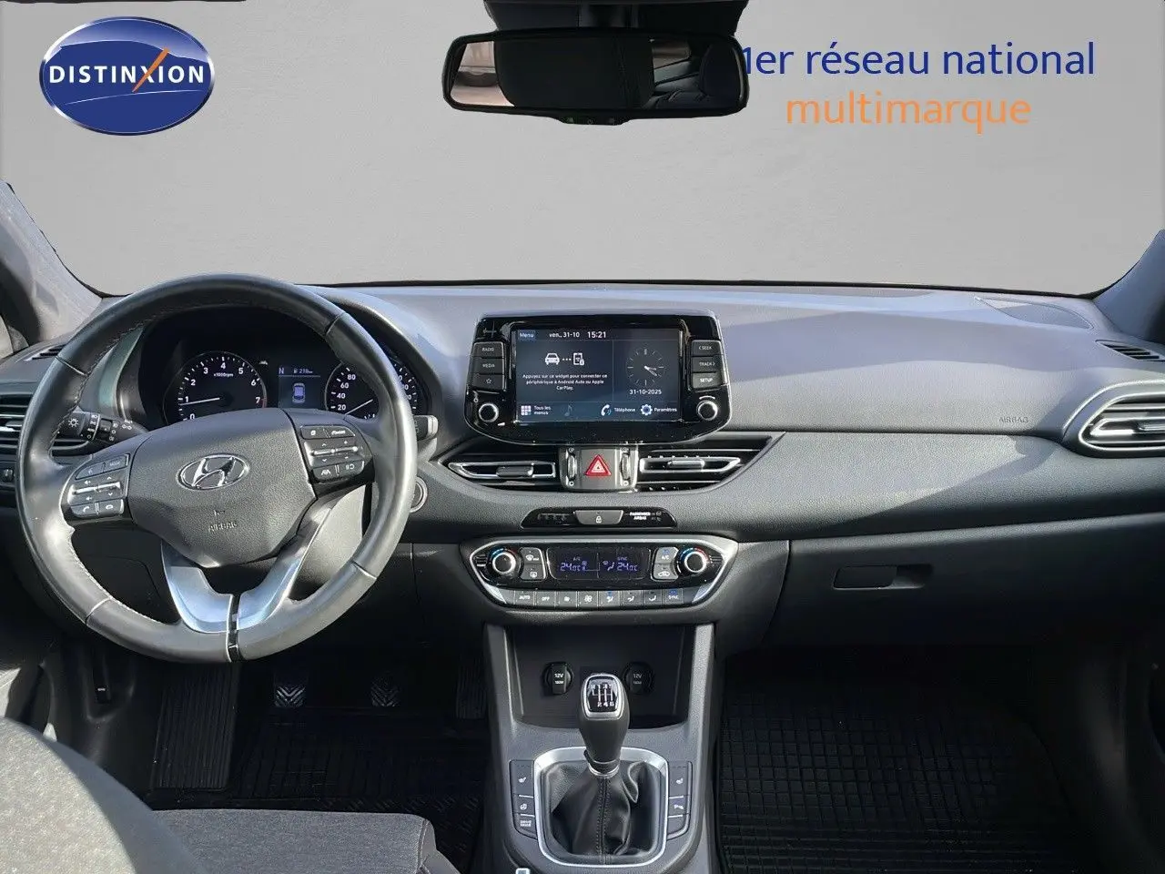 Vue intérieure frontale du tableau de bord de la Hyundai i30 SW 2024 avec volant multifonction et écran tactile central.