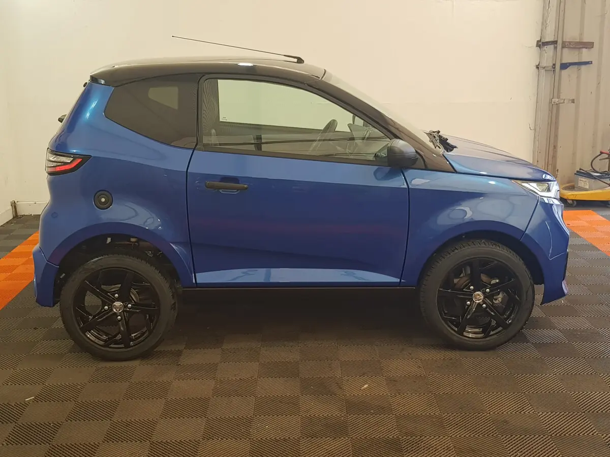 Vue de profil côté gauche d'une Aixam Ambition 0.5 City Sport bleu avec toit noir et jantes noires.