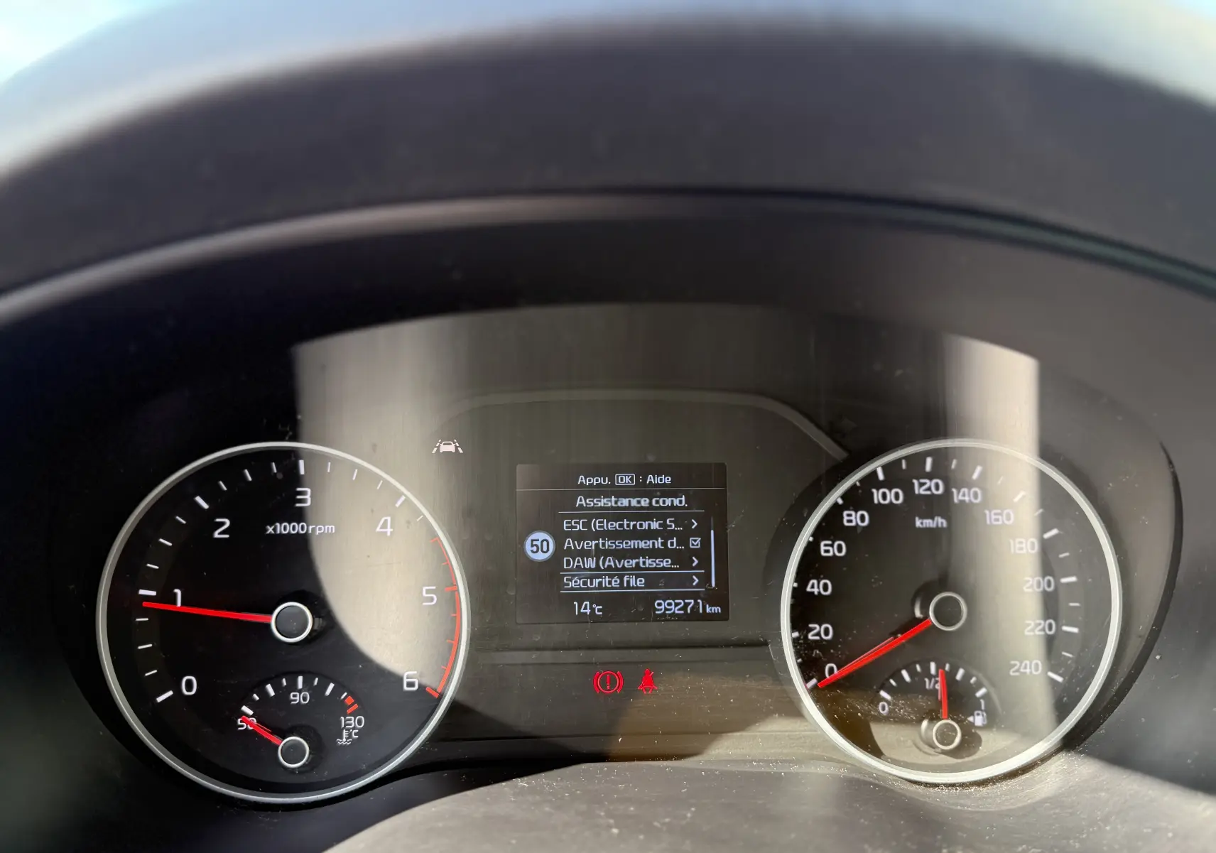 Vue rapprochée du tableau de bord du Kia Sportage bleu 2021, affichant compte-tours, vitesse et écran d'assistance conducteur.