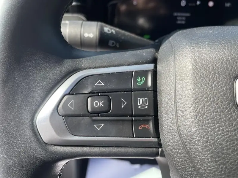 Gros plan sur les commandes au volant côté gauche du Jeep Compass 2023, boutons noirs avec icônes vertes et rouges.
