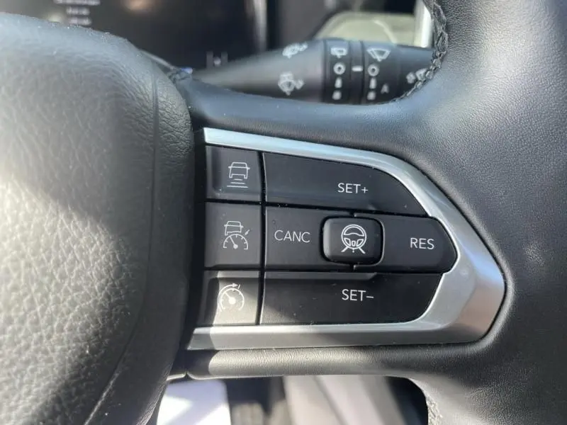 Gros plan sur les commandes du régulateur de vitesse au volant d’un Jeep Compass gris métal 2023.
