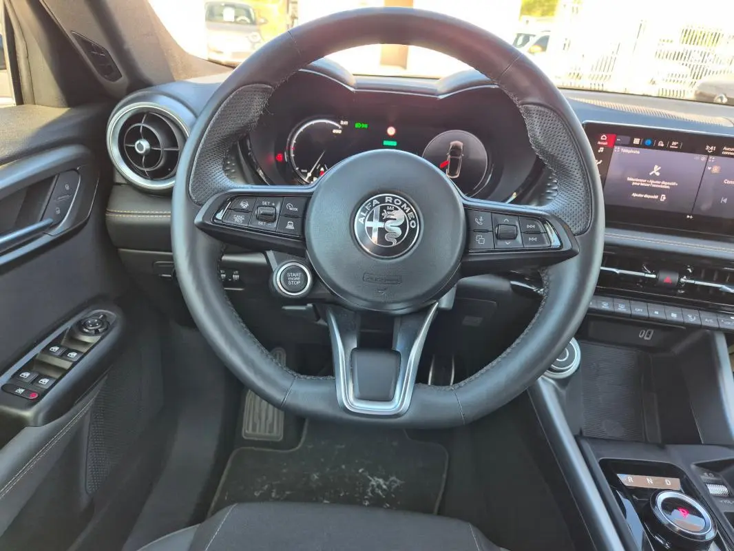 Vue intérieure centrée sur le volant sport de l'Alfa Romeo Tonale 2025, avec tableau de bord numérique et commandes au volant.