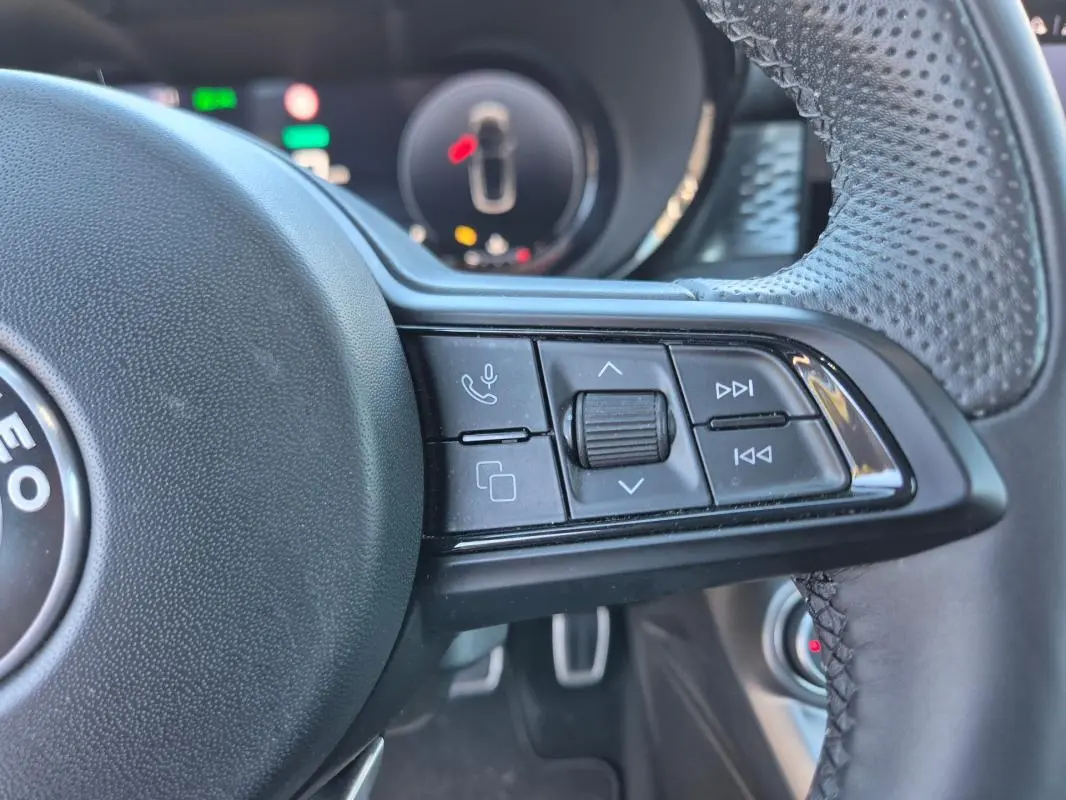 Gros plan sur les commandes multifonctions à droite du volant sport de l'Alfa Romeo Tonale bleu 2025.