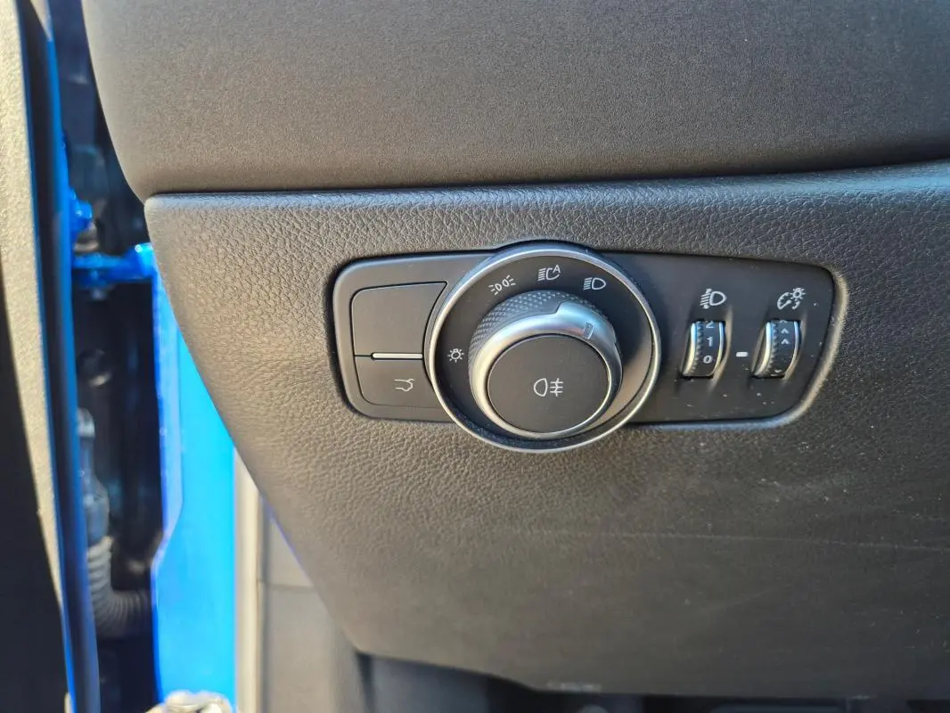 Gros plan sur les commandes d’éclairage intérieures d’une Alfa Romeo Tonale bleu, avec molette et réglages lumineux.