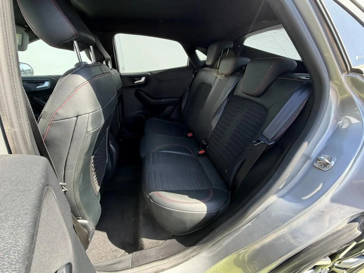 Vue intérieure côté droit de la banquette arrière noire avec surpiqûres rouges du Ford Puma gris métal 2020 ST-Line X.