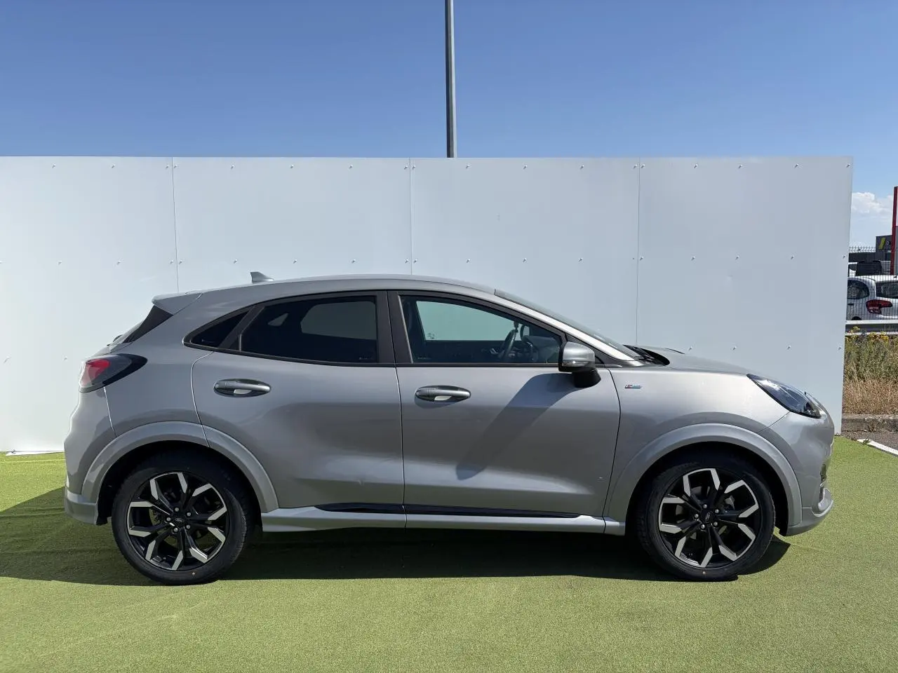Vue latérale droite d'un Ford Puma gris métal avec jantes alliage noires et badges ST-Line visibles.