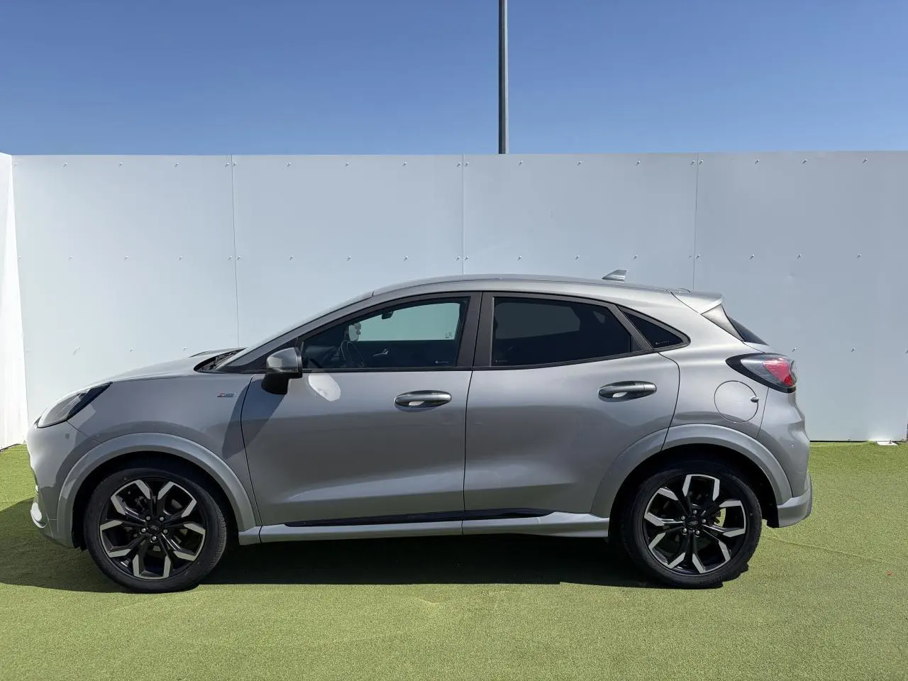 Vue latérale droite du Ford Puma gris métal, mettant en valeur ses jantes alliage noires et ses vitres arrière surteintées.