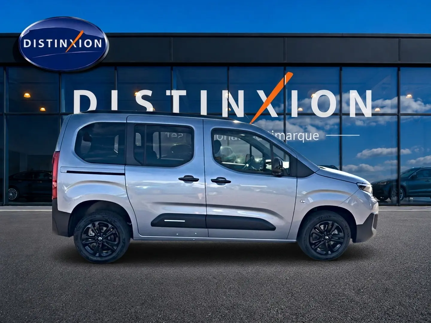 Profil droit du Citroën Berlingo N1 1.5 BlueHDi 130 gris acier avec jantes noires et barres de toit visibles.