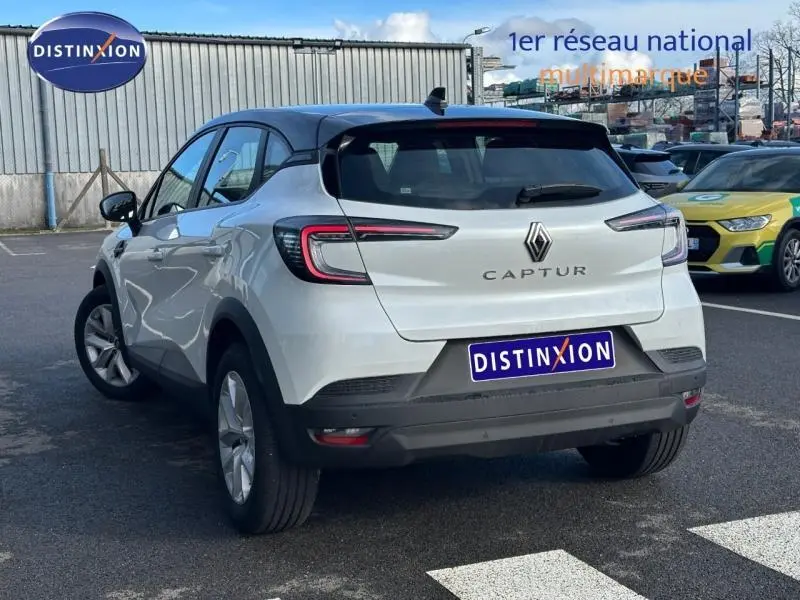 Vue 3/4 arrière d'un Renault Captur blanc nacré avec toit noir et feux arrière LED, stationné en extérieur.