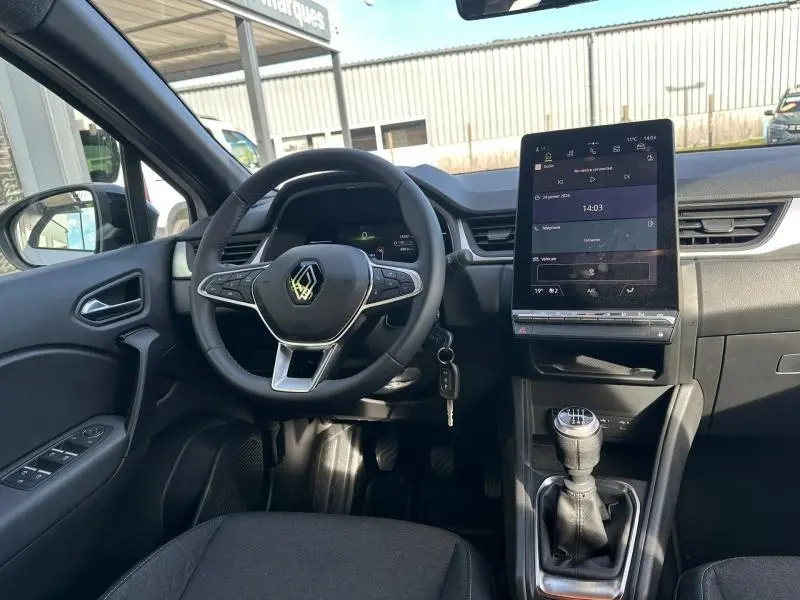 Vue intérieure avant du Renault Captur 2025 avec volant multifonction, écran tactile vertical et levier de vitesse manuel.