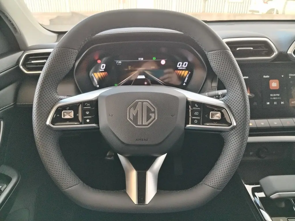Vue frontale du volant perforé noir du MG MOTOR ZS 1.5 l Hybrid + 197 LUXURY avec tableau de bord numérique et écran tactile.