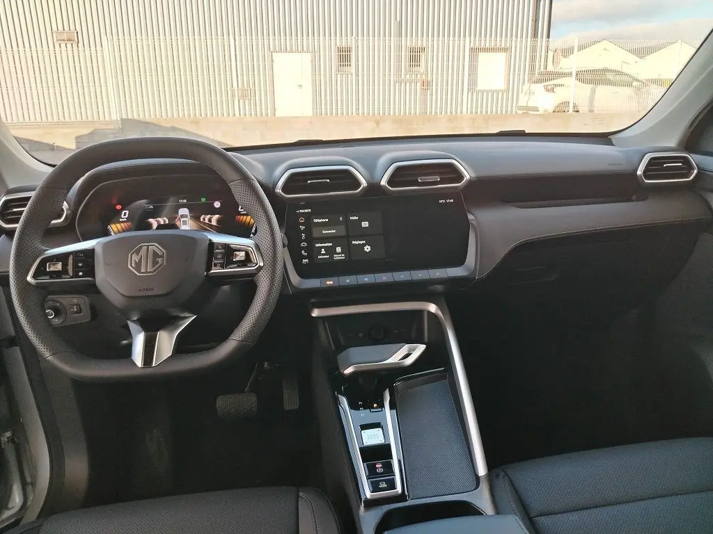 Vue intérieure frontale du tableau de bord et volant noir du MG ZS 1.5 l Hybrid + 197 Luxury, avec écran tactile central.
