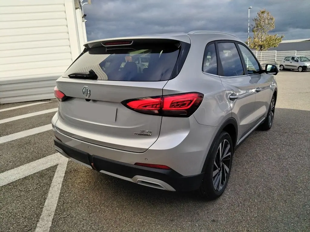 Vue 3/4 arrière droite du MG ZS 1.5 l Hybrid Cosmic Silver, avec feux arrière LED et jantes alliage distinctives.