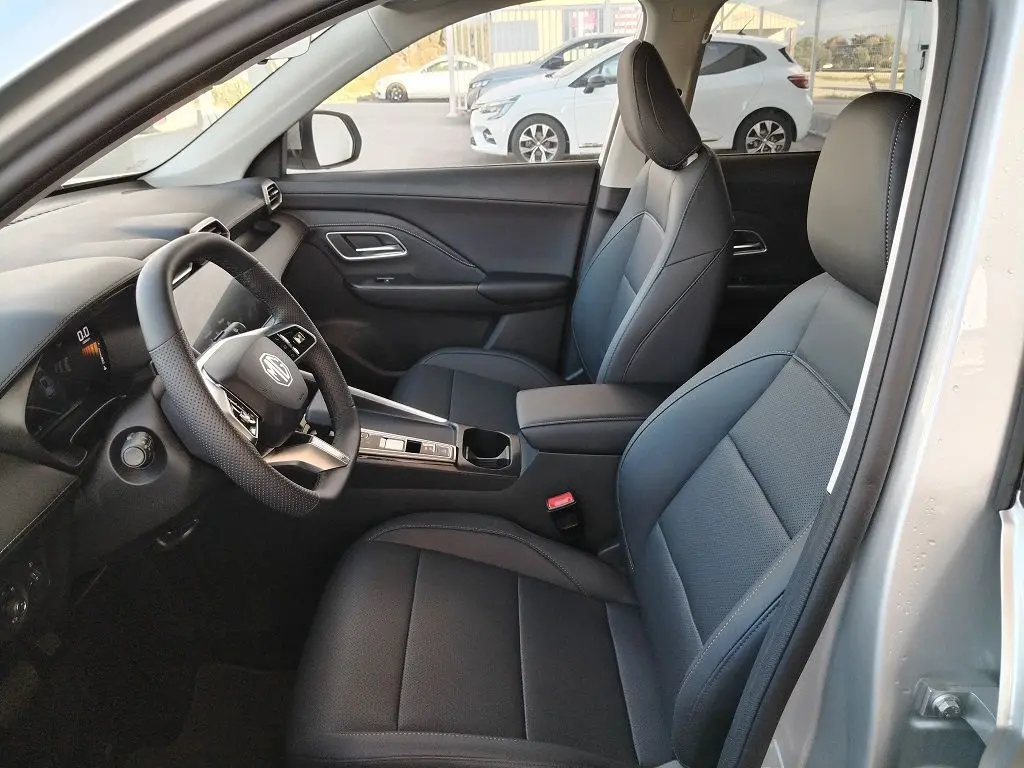 Vue intérieure côté conducteur du MG MOTOR ZS 1.5 l Hybrid 2026 en Cosmic Silver, sièges cuir noir et tableau de bord moderne.