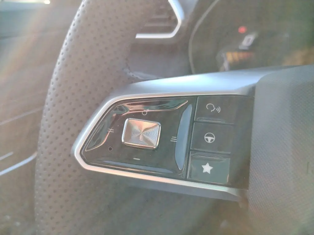 Gros plan sur les commandes du volant côté gauche du MG MOTOR ZS 1.5 l Hybrid + 197 LUXURY en intérieur noir.