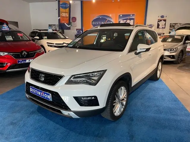 SUV SEAT Ateca blanc Nevada vu en 3/4 avant droit dans un showroom avec moquette bleue et éclairage intérieur.