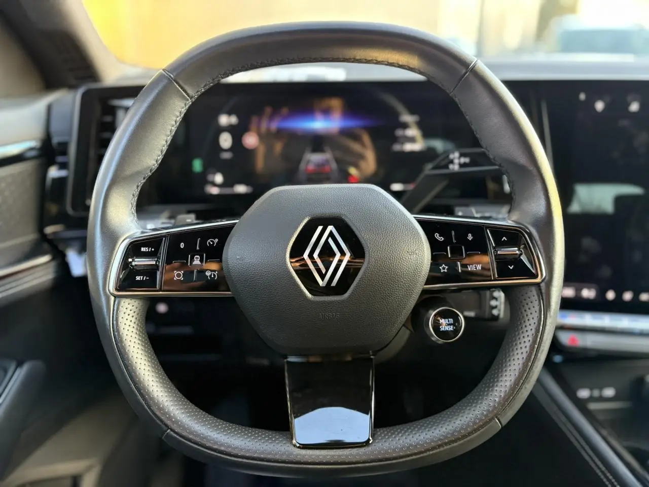 Volant cuir noir perforé Renault Australe 2023 avec commandes intégrées et tableau de bord numérique en arrière-plan