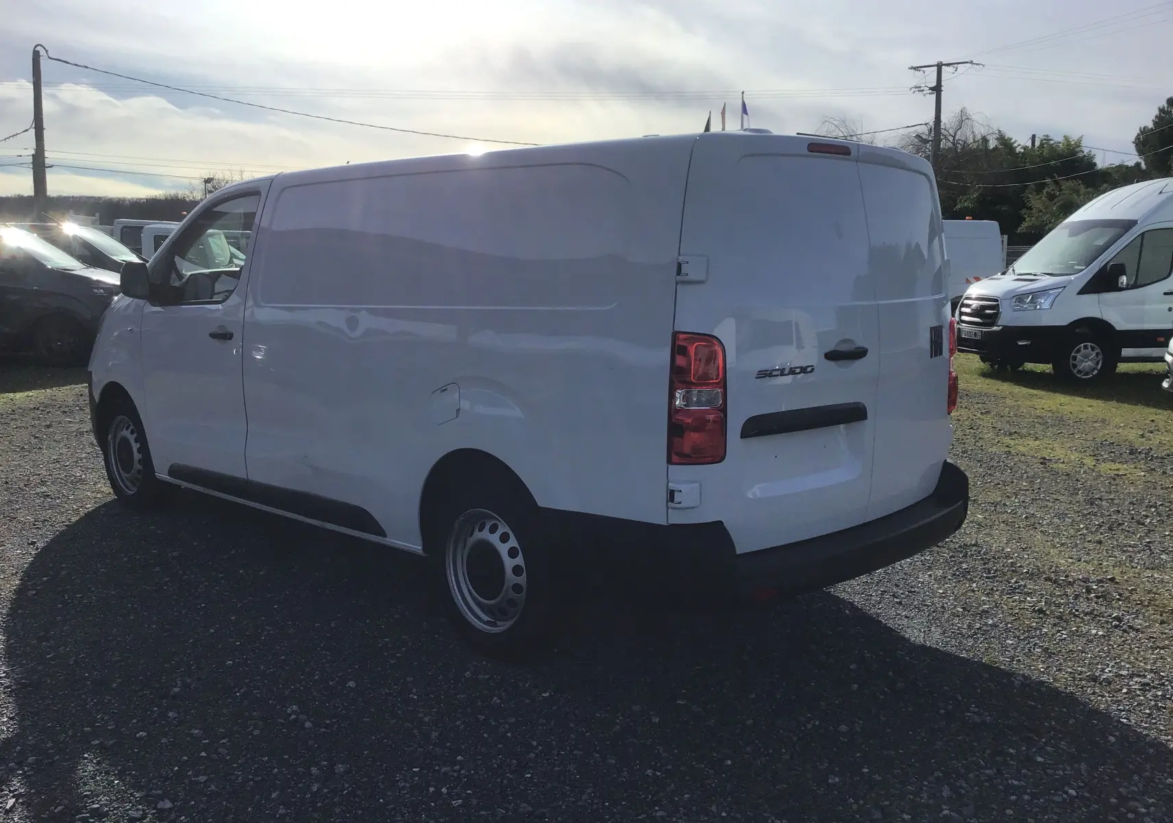 Fiat Scudo Fourgon blanc vu en 3/4 arrière droit, avec garde au sol réhaussée et plaque de protection tôlée.