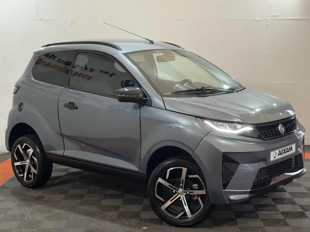 Vue 3/4 avant d'une Aixam Ambition 0.5 Crossover Premium gris foncé avec jantes noires et rétroviseur caméra côté gauche.