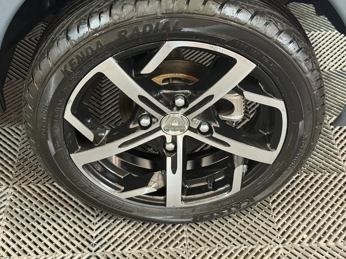 Gros plan sur la jante noire et argentée d’une Aixam Ambition 0.5 Crossover Premium gris foncé, roue avant.