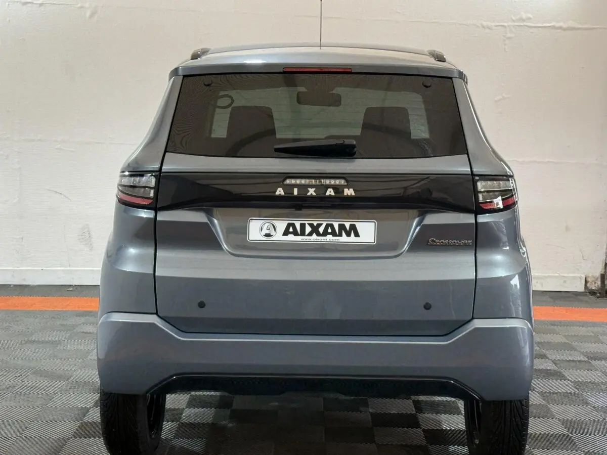 Vue arrière d'une Aixam Ambition 0.5 Crossover Premium gris foncé avec logo et feux horizontaux distinctifs.
