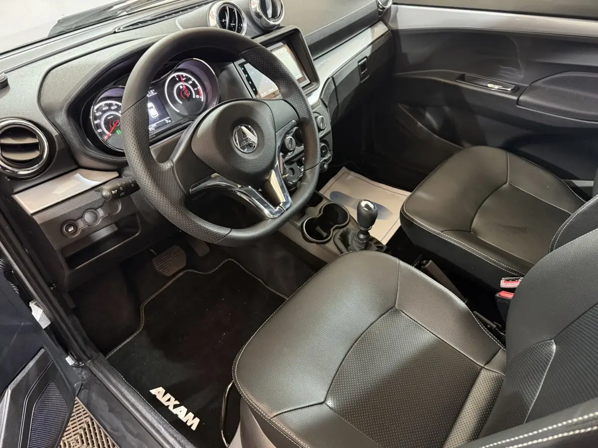 Vue intérieure de l'AIXAM AMBITION 0.5 CROSSOVER PREMIUM 2026, montrant le tableau de bord et les sièges en cuir noir.