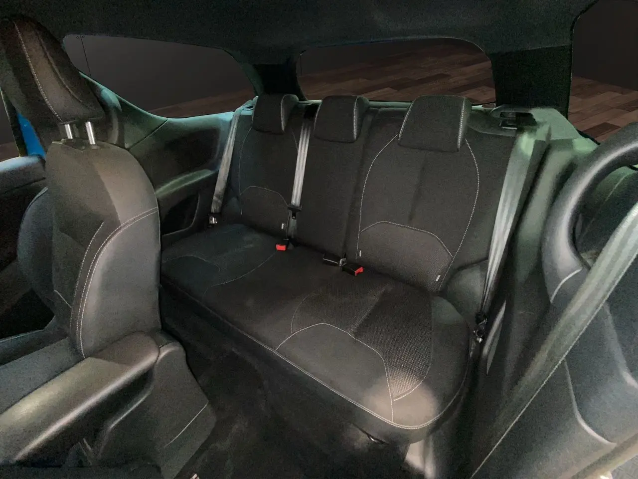 Vue intérieure arrière montrant la banquette arrière en tissu noir de la Citroën DS3 2011 avec ceintures de sécurité visibles.