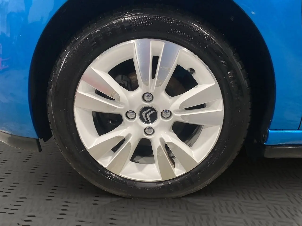 Gros plan sur la roue avant droite d'une Citroën DS3 bleu avec jante alliage blanche et logo Citroën central.