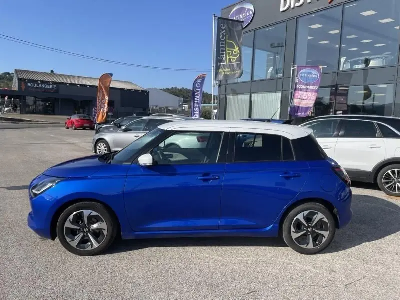 Suzuki Swift 1.2 Dualjet Hybrid 2024 bleu métal vue de profil côté gauche avec toit blanc et jantes distinctives.