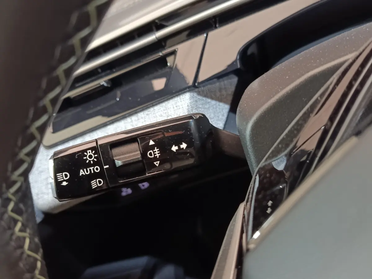 Gros plan sur la commande des phares et clignotants du Peugeot 5008 gris clair, intérieur côté gauche.