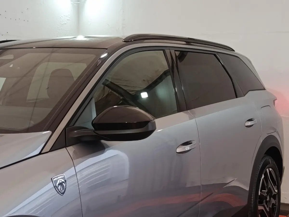 Vue latérale droite du Peugeot 5008 gris clair 2026 avec logo lion et vitres teintées.