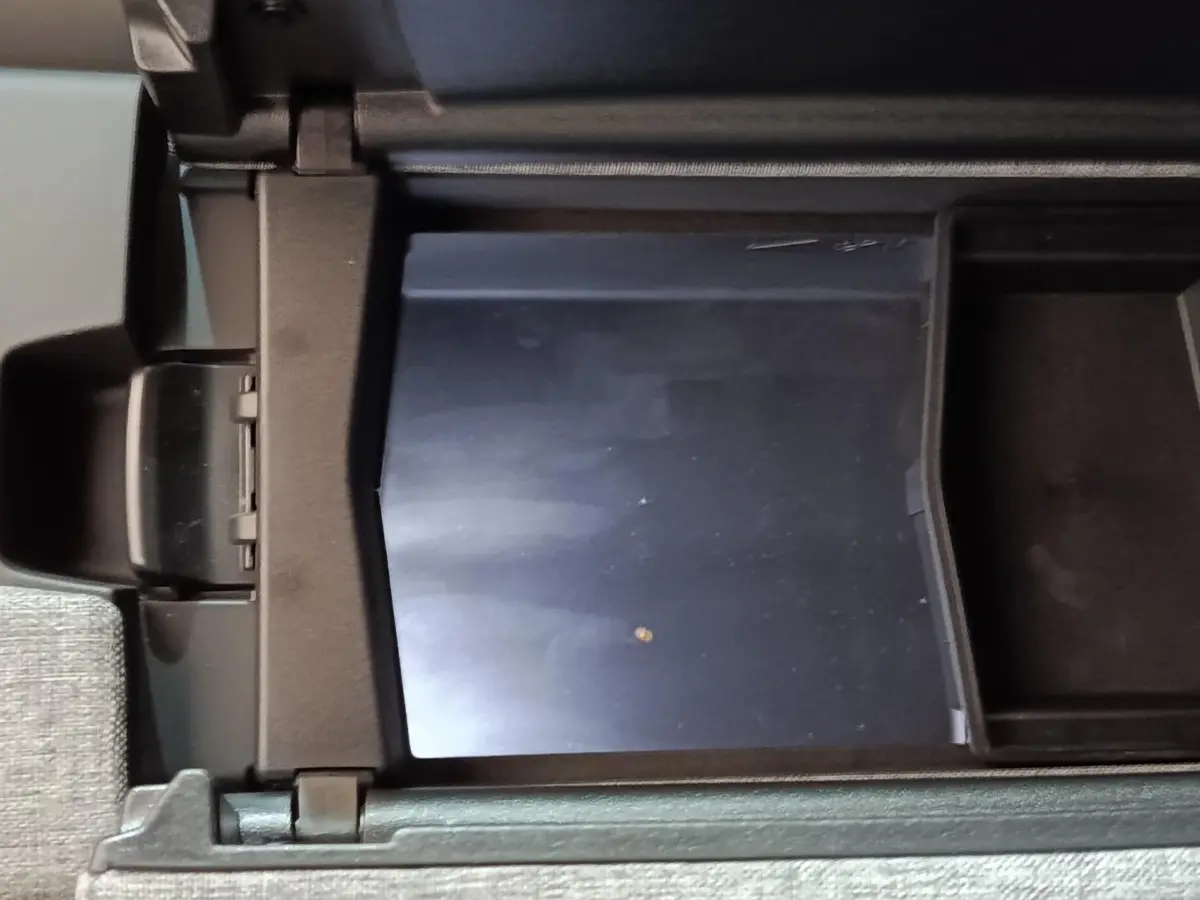 Vue rapprochée de la console centrale ouverte du Peugeot 5008 gris clair, montrant un compartiment de rangement intérieur.