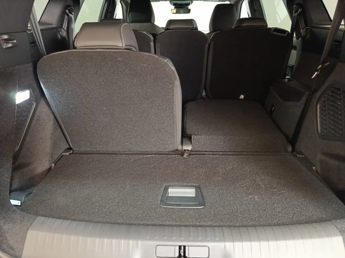 Vue arrière intérieure du coffre du Peugeot 5008 gris clair avec sièges rabattus partiellement à droite.
