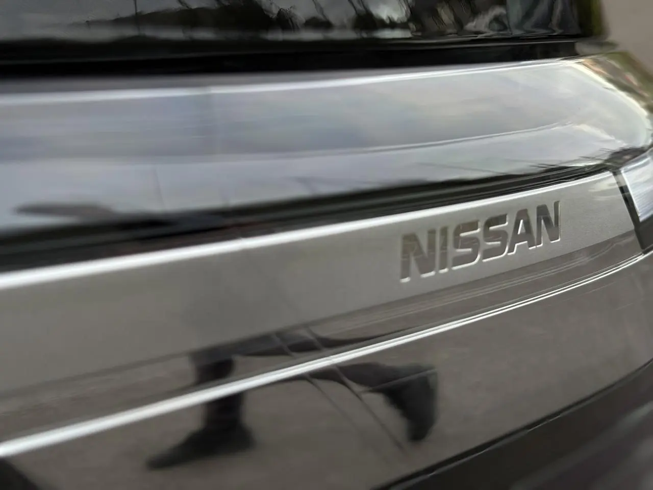 Gros plan sur la calandre noire métallisée du Nissan Primastar Combi avec logo Nissan en relief.