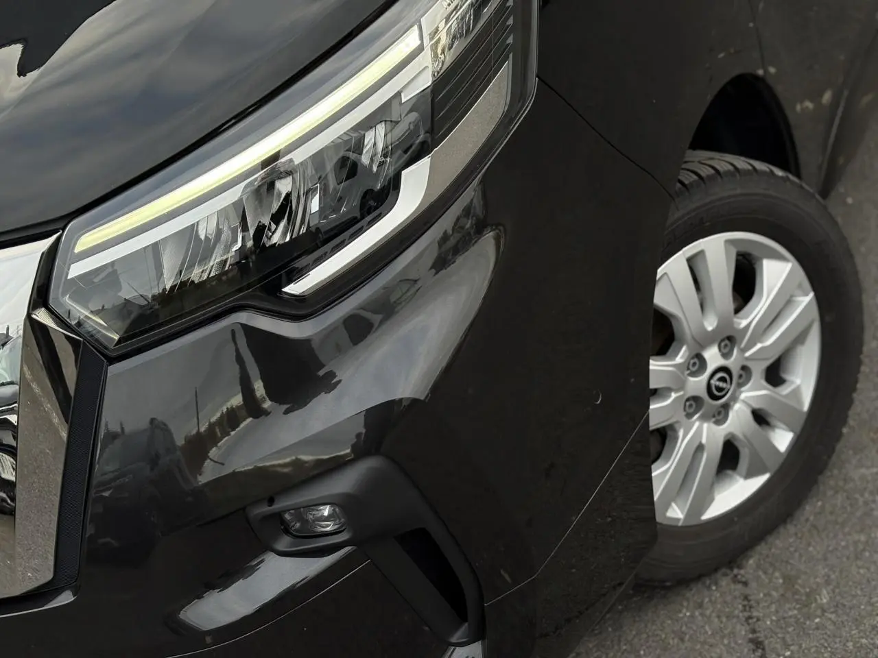 Gros plan sur l'avant droit noir métallisé du Nissan Primastar Combi, mettant en valeur le phare LED et la jante alliage.