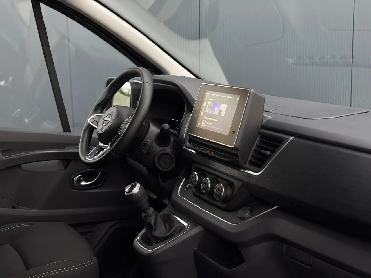 Intérieur côté conducteur du Nissan Primastar Combi 2025 noir, avec tableau de bord moderne et écran tactile central.