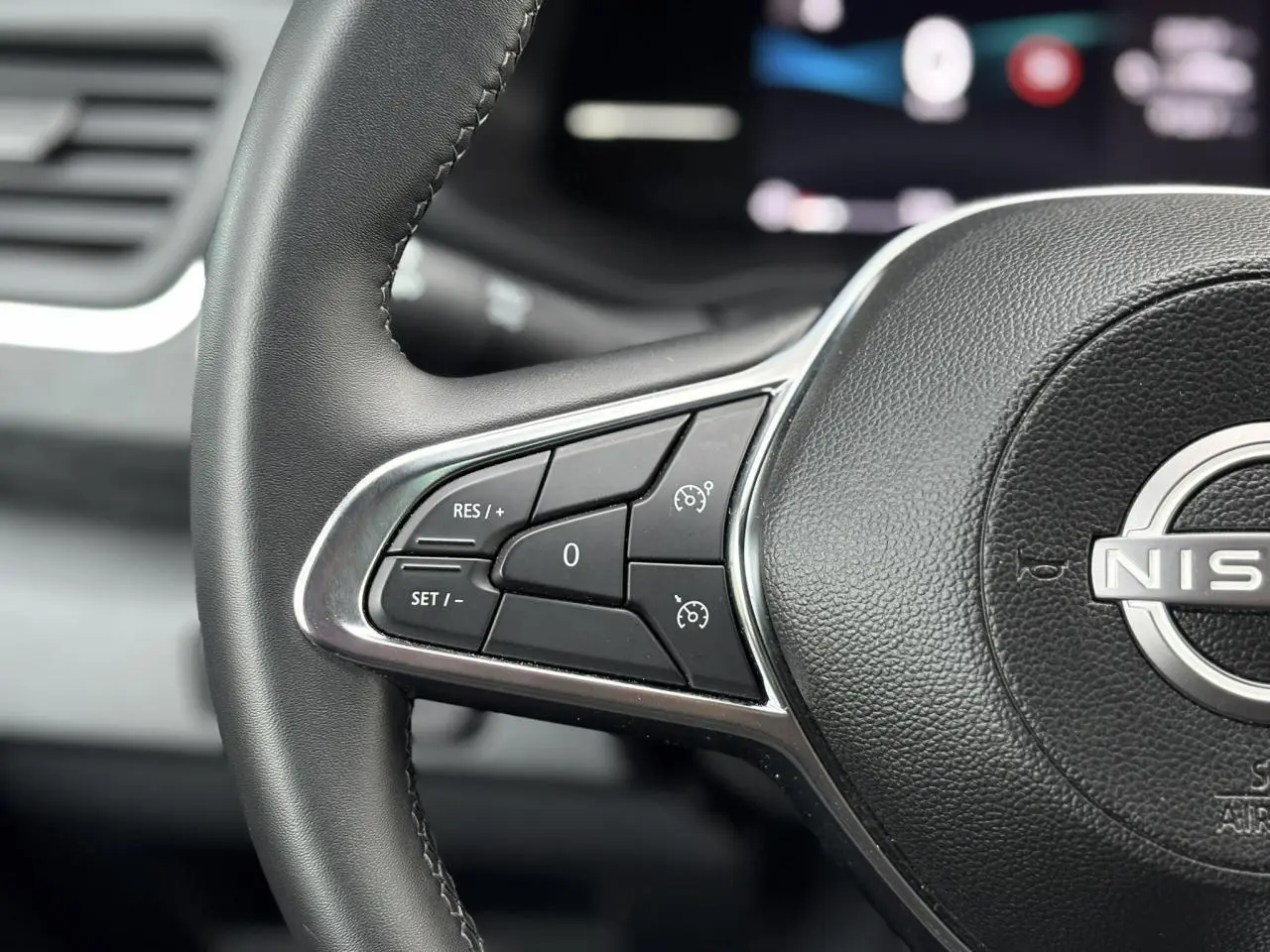 Gros plan sur le volant noir du Nissan Primastar Combi 2025, mettant en valeur les commandes de régulateur de vitesse.