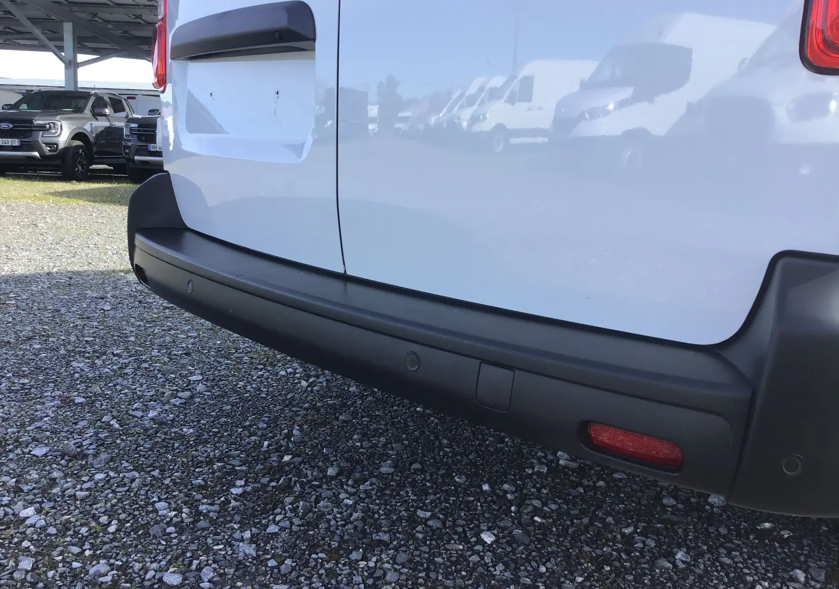 Gros plan sur le pare-chocs arrière noir du FIAT Scudo Fourgon blanc, avec capteurs de recul visibles.