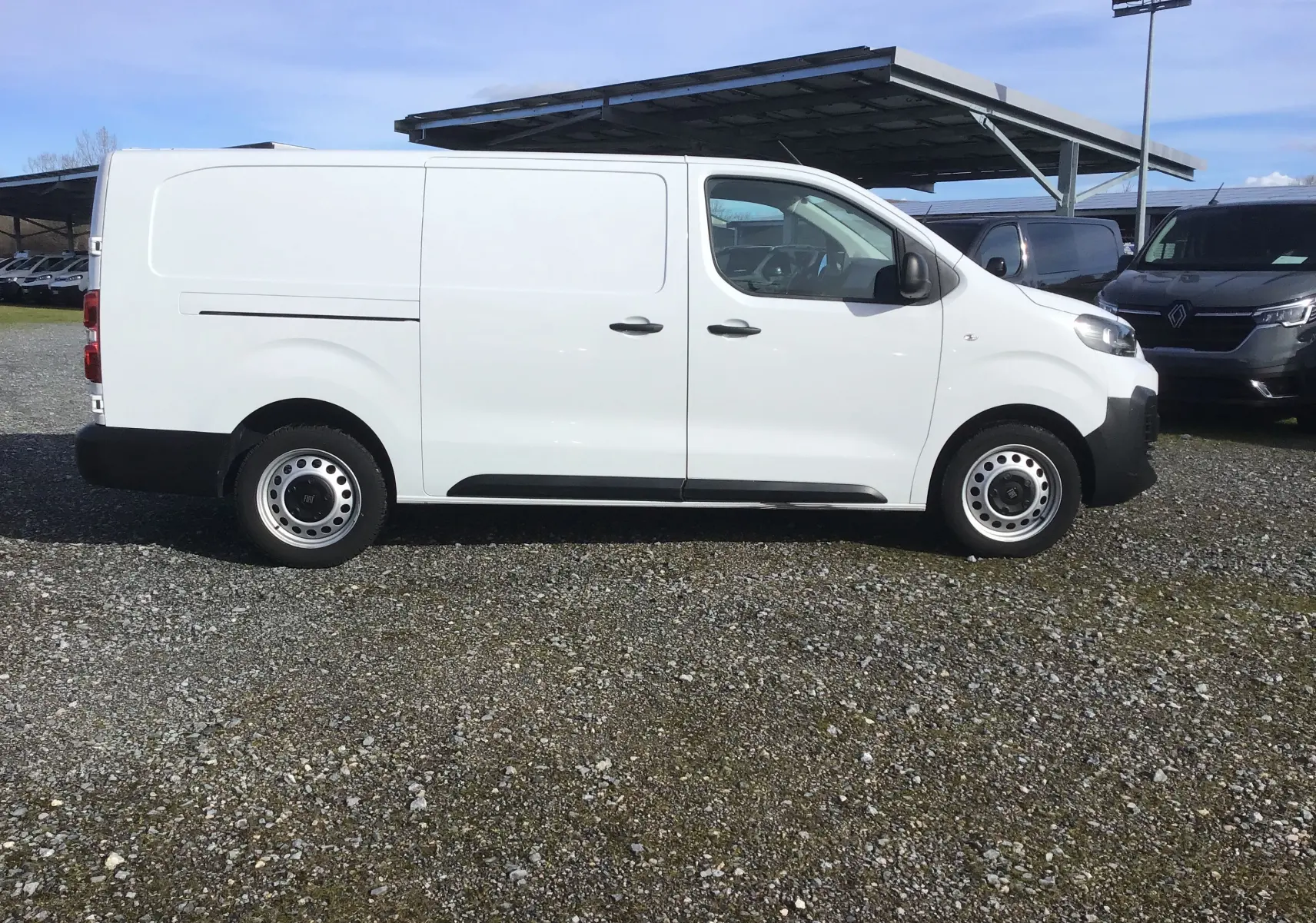 Vue de profil côté gauche d’un FIAT Scudo Fourgon blanc 2024 avec garde au sol réhaussée et jantes acier.