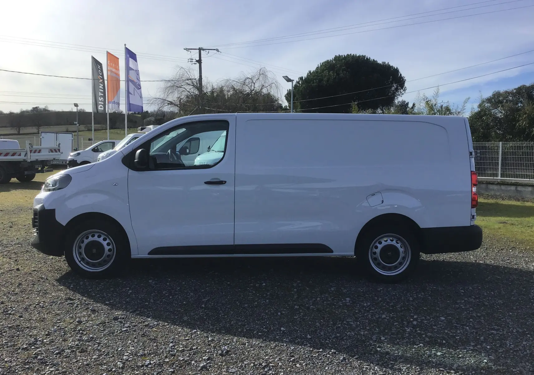 Vue latérale gauche d’un FIAT Scudo Fourgon blanc 2024, version XL avec garde au sol réhaussée et plaque de protection tôlée.