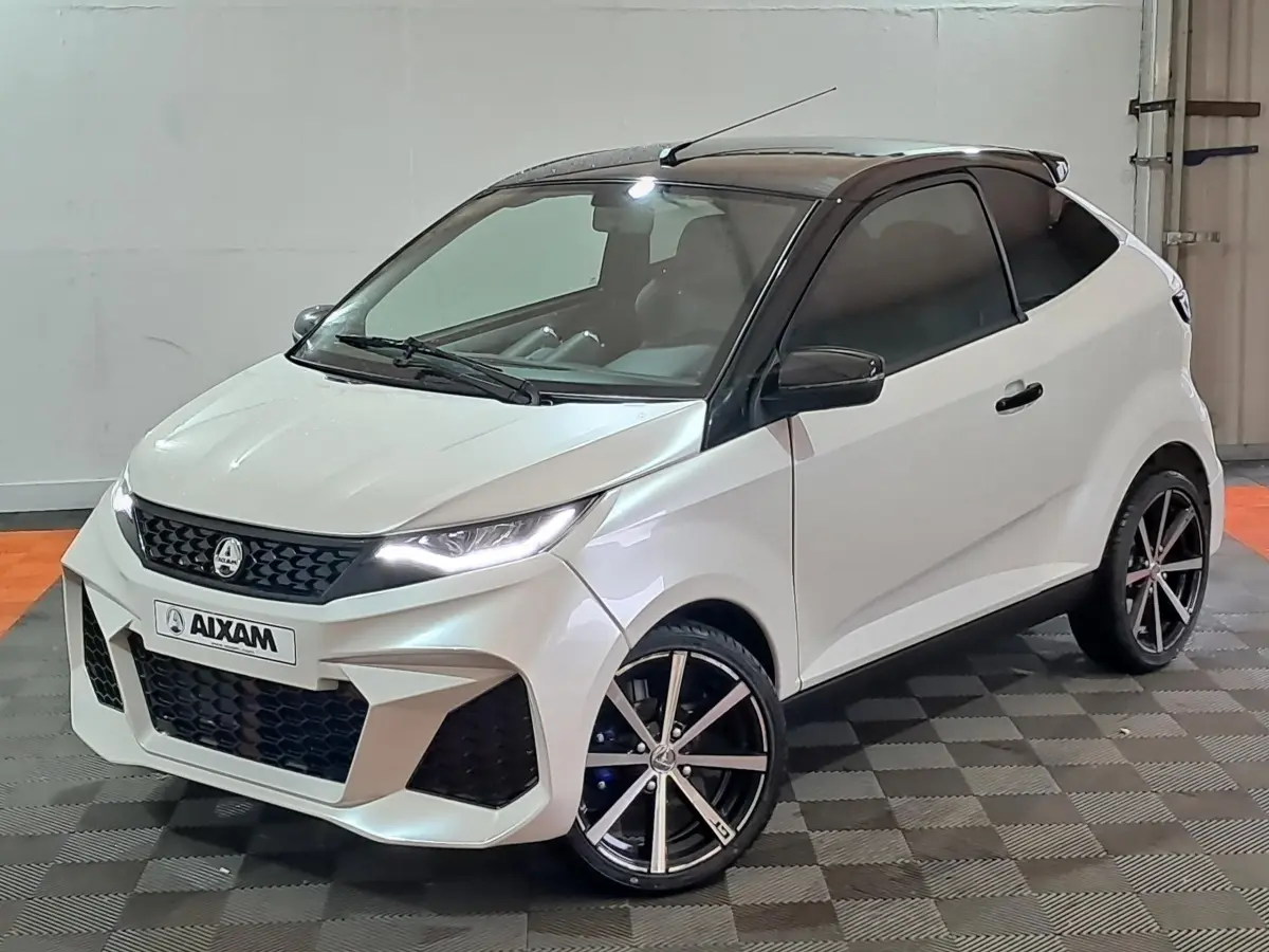 Vue 3/4 avant d'une Aixam Ambition 0.5 City Coupe GTI blanche avec toit noir et jantes alliage noires.