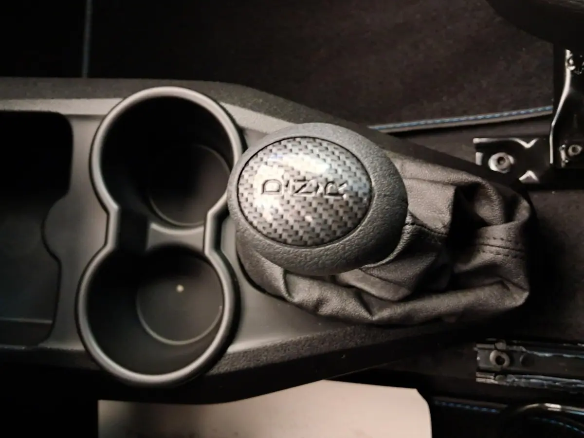 Gros plan sur le levier de vitesses DIZAL en carbone et les porte-gobelets noirs de l'AIXAM AMBITION 0.5 CITY COUPE GTI blanc.